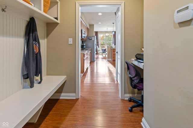 mudroom featuring wood-type flooring and an inviting chandelier