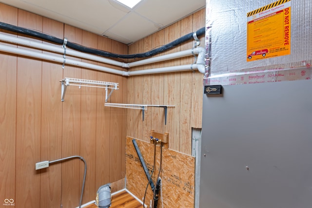 interior details featuring a paneled ceiling, heating unit, wood walls, and hardwood / wood-style flooring