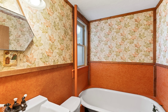 bathroom featuring toilet, wooden walls, and a bathtub