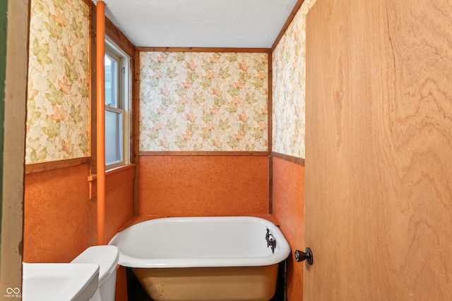 bathroom with toilet, ornamental molding, and a bathtub