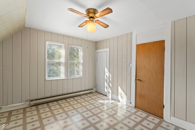 empty room with wood walls, baseboard heating, and ceiling fan