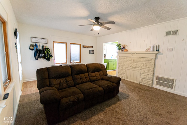 living room with carpet, a textured ceiling, ceiling fan, and wooden walls