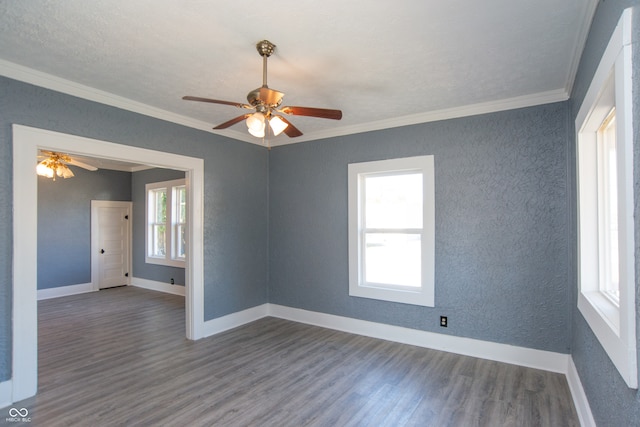 unfurnished room with dark wood-type flooring, ceiling fan, a healthy amount of sunlight, and ornamental molding