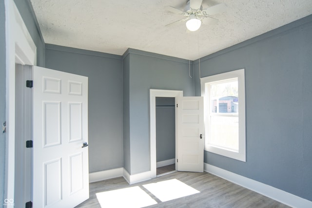 unfurnished bedroom with ceiling fan, a textured ceiling, and light hardwood / wood-style flooring