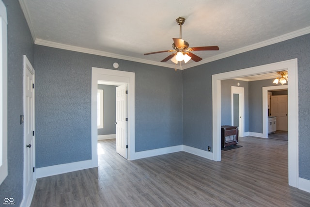 unfurnished room with crown molding, a wood stove, and dark hardwood / wood-style floors