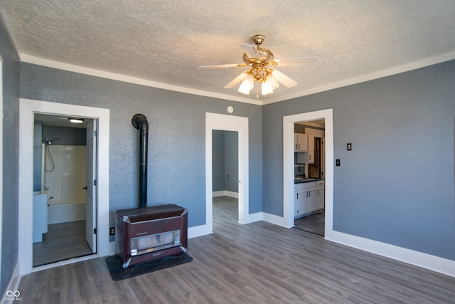 living room with a wood stove, a textured ceiling, dark wood-type flooring, and ceiling fan