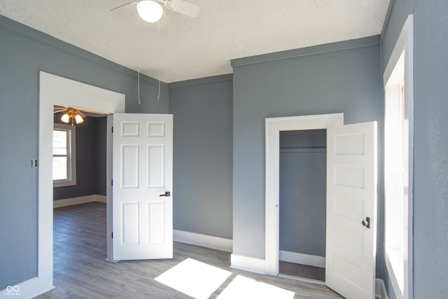 unfurnished bedroom featuring a closet, ceiling fan, a textured ceiling, and light wood-type flooring