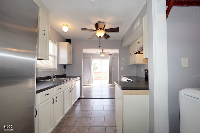 kitchen with range, stainless steel refrigerator, washer / clothes dryer, and white cabinets