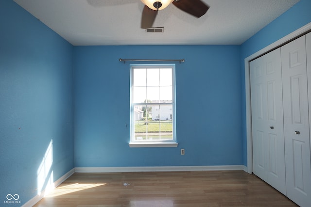 unfurnished bedroom with a closet, ceiling fan, a textured ceiling, and hardwood / wood-style floors