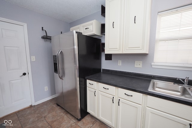 kitchen with sink, a textured ceiling, stainless steel fridge, white cabinetry, and light tile patterned floors