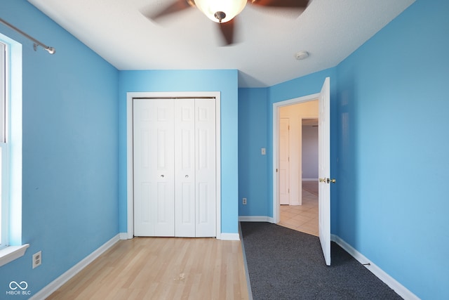 unfurnished bedroom featuring a closet, light wood-type flooring, and ceiling fan