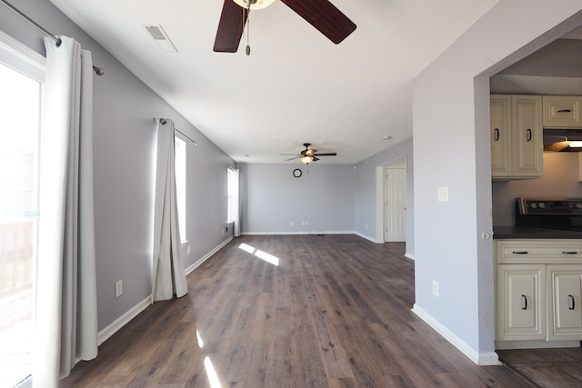 unfurnished living room with a healthy amount of sunlight, dark wood-type flooring, and ceiling fan