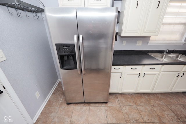 kitchen featuring white cabinets, sink, and stainless steel fridge