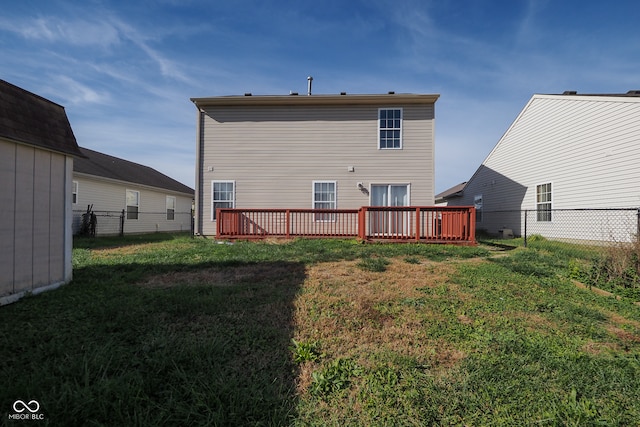 rear view of house with a wooden deck and a lawn