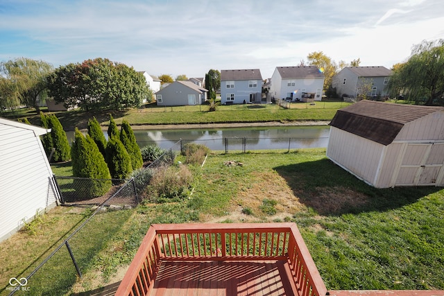 view of yard featuring a deck with water view and a storage shed