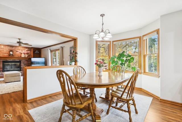 dining room featuring a fireplace, ceiling fan with notable chandelier, and light wood-type flooring