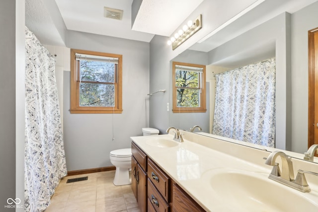 bathroom featuring a healthy amount of sunlight, vanity, toilet, and tile patterned floors