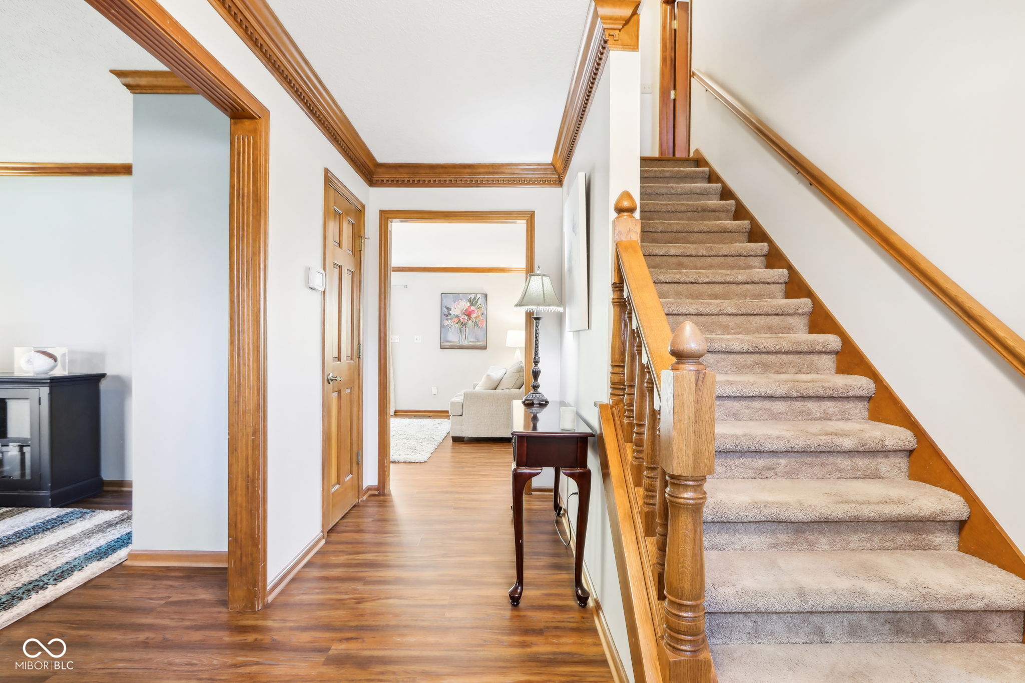 staircase with hardwood / wood-style floors and crown molding