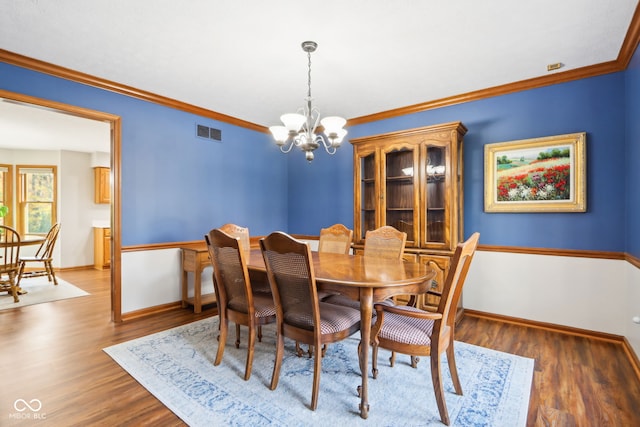 dining room featuring ornamental molding, dark wood-type flooring, and a chandelier