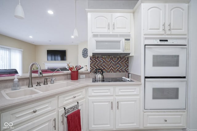 kitchen featuring white appliances, decorative light fixtures, and white cabinetry