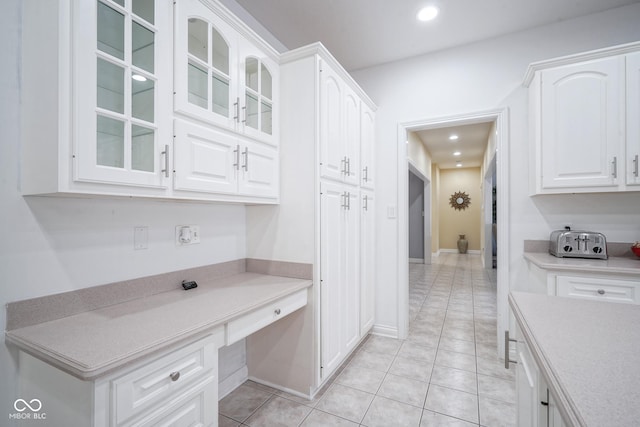 kitchen with light tile patterned floors, built in desk, and white cabinetry