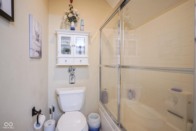 bathroom with toilet and shower / bath combination with glass door