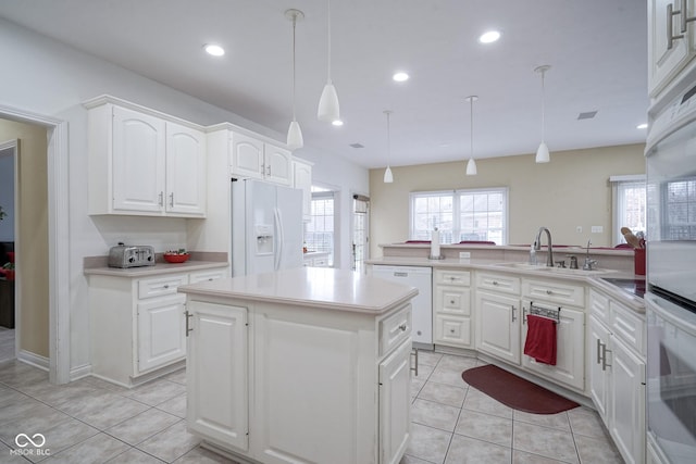 kitchen with kitchen peninsula, white appliances, pendant lighting, white cabinets, and a kitchen island