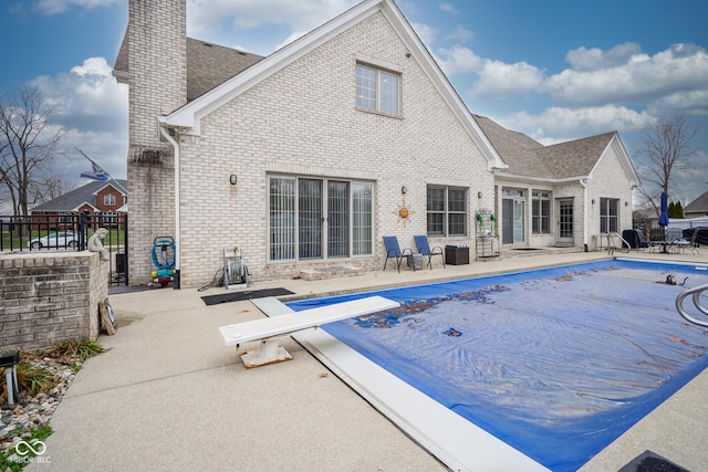 rear view of house featuring a patio and a covered pool