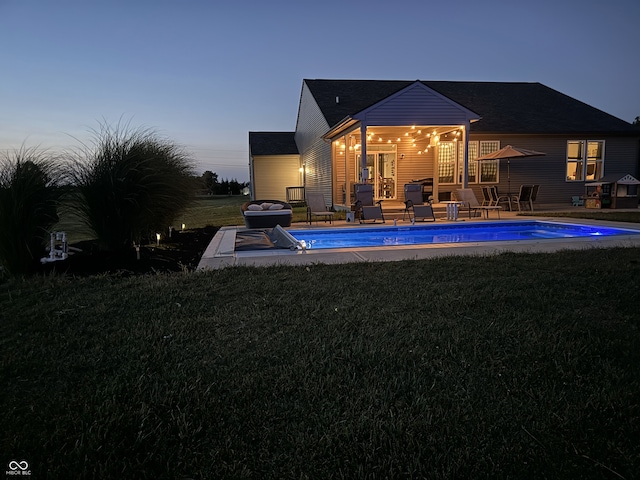 pool at dusk with a patio and a yard