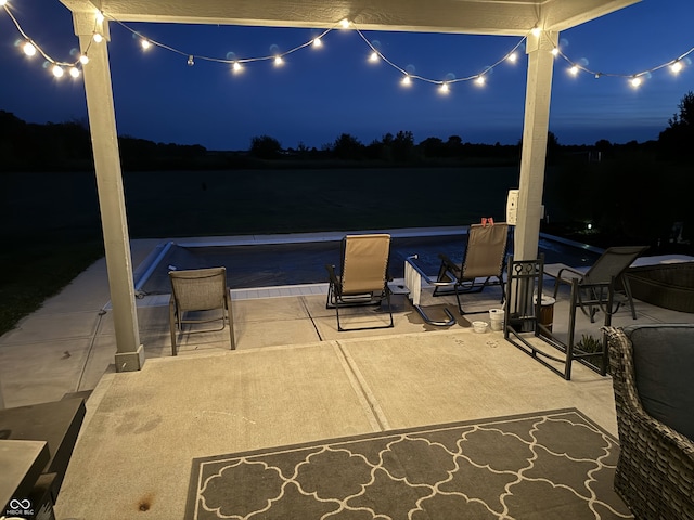 patio at night featuring a water view