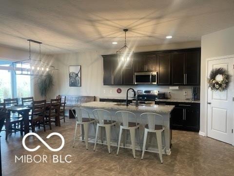 kitchen with a sink, appliances with stainless steel finishes, a center island with sink, and a breakfast bar