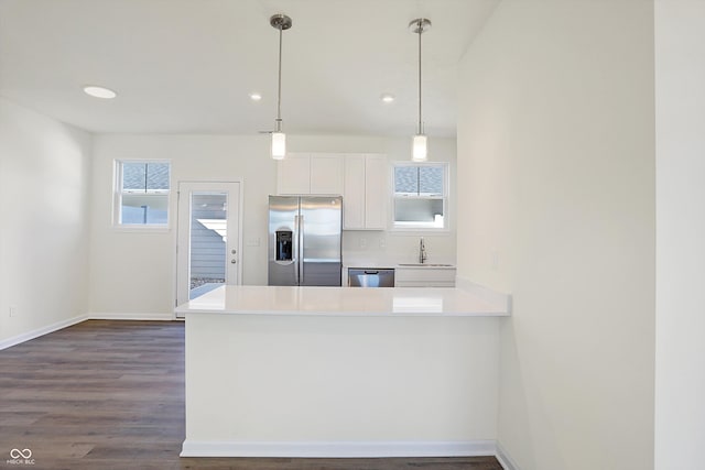 kitchen with appliances with stainless steel finishes, kitchen peninsula, pendant lighting, and plenty of natural light