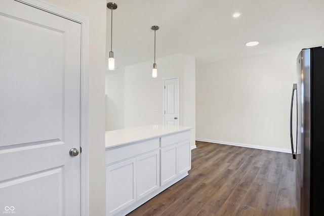 kitchen featuring white cabinets, hanging light fixtures, dark hardwood / wood-style flooring, and stainless steel fridge