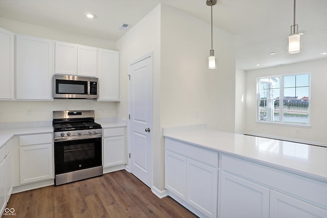 kitchen featuring kitchen peninsula, dark hardwood / wood-style flooring, appliances with stainless steel finishes, white cabinetry, and pendant lighting