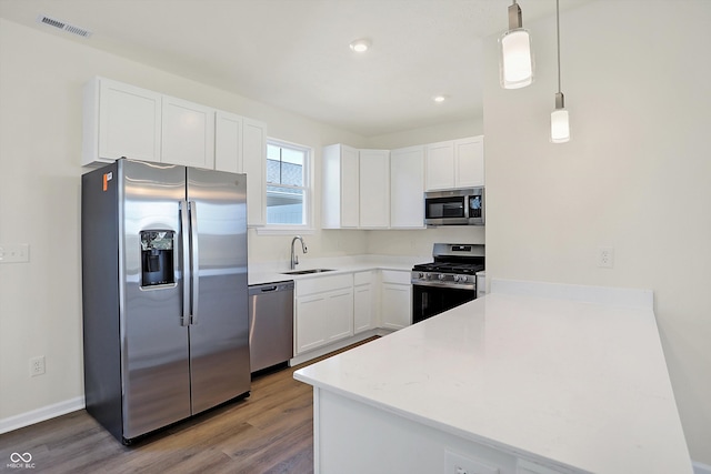 kitchen featuring hardwood / wood-style flooring, stainless steel appliances, sink, and white cabinets