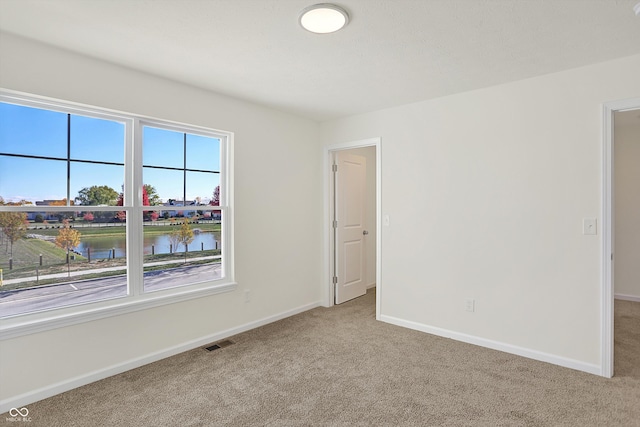 carpeted spare room featuring a water view