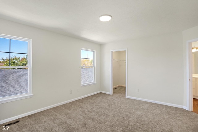 unfurnished bedroom with light carpet, a walk in closet, and a closet