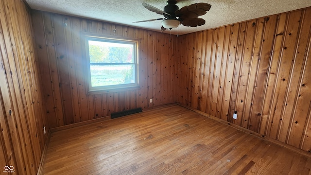 2620 Wicker Rd, Indianapolis, IN 46217 - empty room featuring a textured ceiling, hardwood / wood-style floors, wooden walls, and ceiling fan