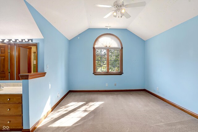 interior space featuring ceiling fan, vaulted ceiling, and light carpet