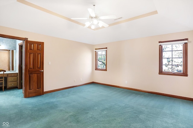 carpeted spare room featuring a tray ceiling and ceiling fan