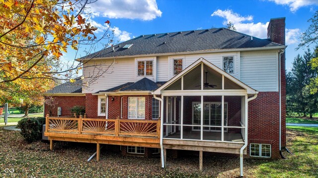 back of house featuring a sunroom, brick siding, a chimney, and roof with shingles