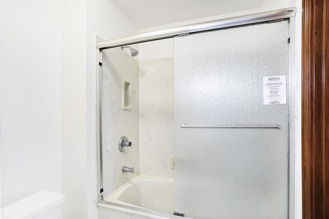 bathroom featuring shower / bath combination with glass door and toilet