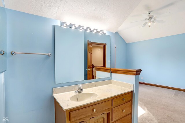 bathroom with vanity, lofted ceiling, ceiling fan, and a textured ceiling