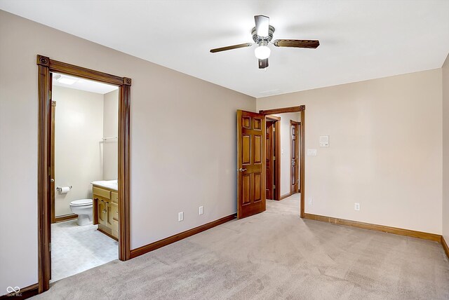 unfurnished bedroom with light carpet, baseboards, a ceiling fan, and ensuite bathroom