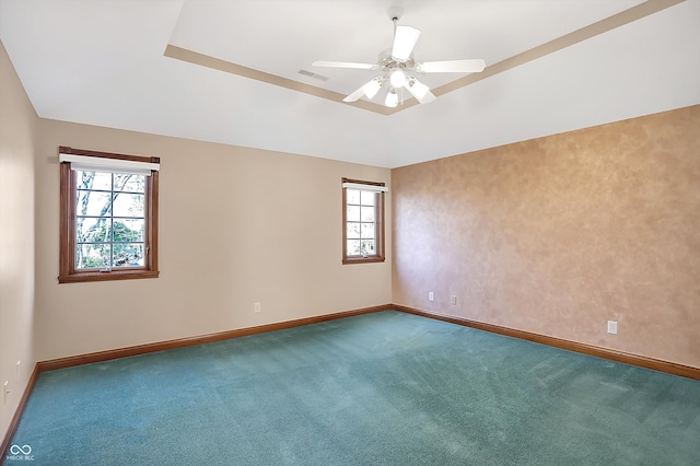 unfurnished room with carpet floors, a tray ceiling, baseboards, and a ceiling fan