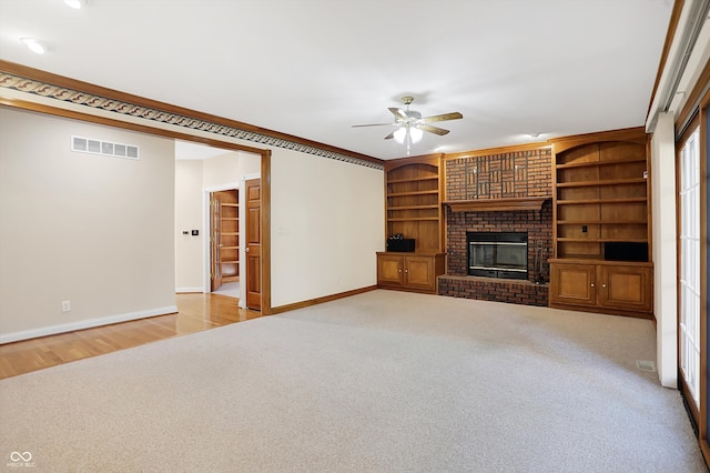 unfurnished living room with light carpet, a brick fireplace, ornamental molding, and ceiling fan