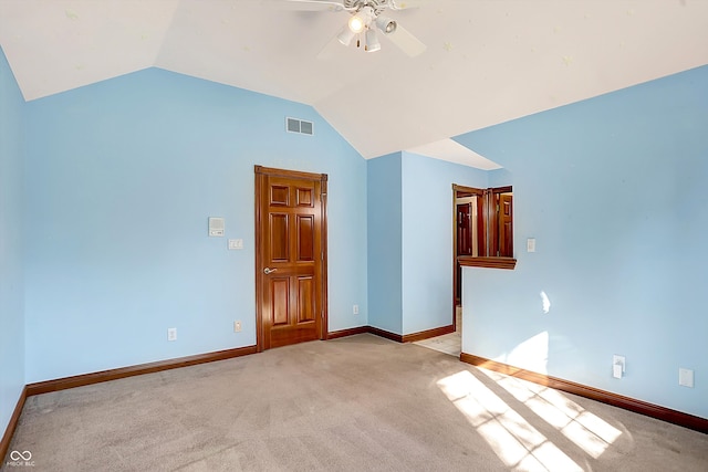 empty room featuring vaulted ceiling, light colored carpet, and ceiling fan