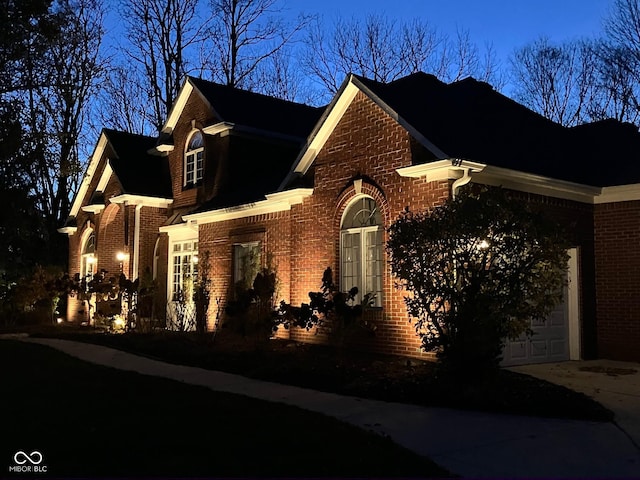 view of side of home with an attached garage, driveway, and brick siding