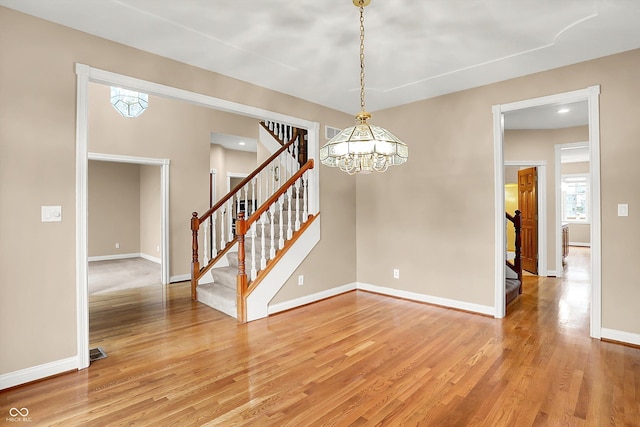 spare room with hardwood / wood-style floors and a chandelier