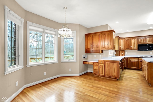 kitchen featuring sink, an inviting chandelier, a center island, hanging light fixtures, and light hardwood / wood-style flooring